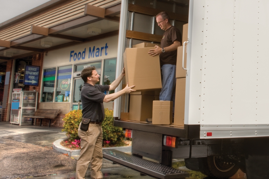 Two men unloading boxes out of truck trailer